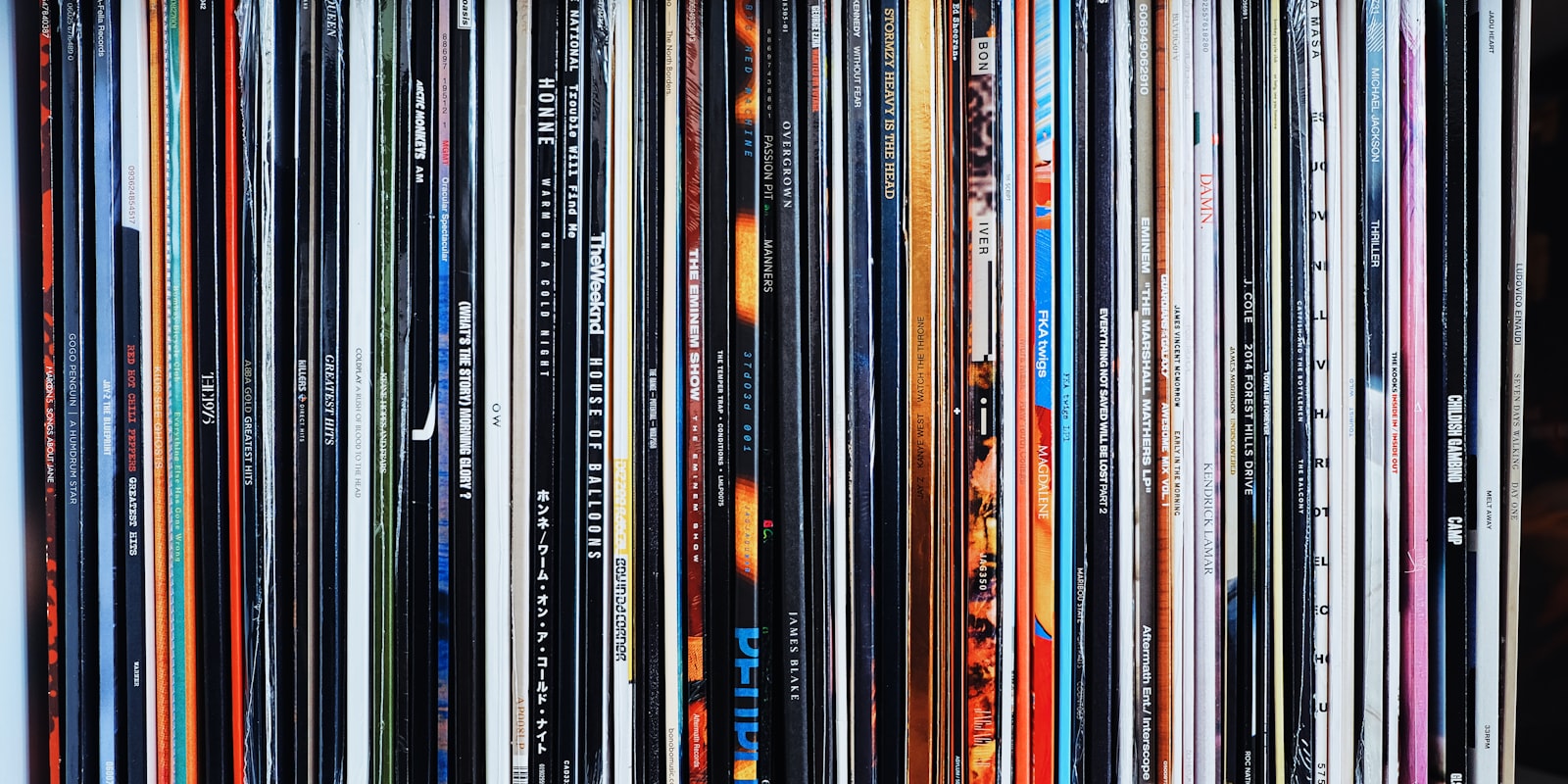 A shelf packed with vinyl record spines of all colors
